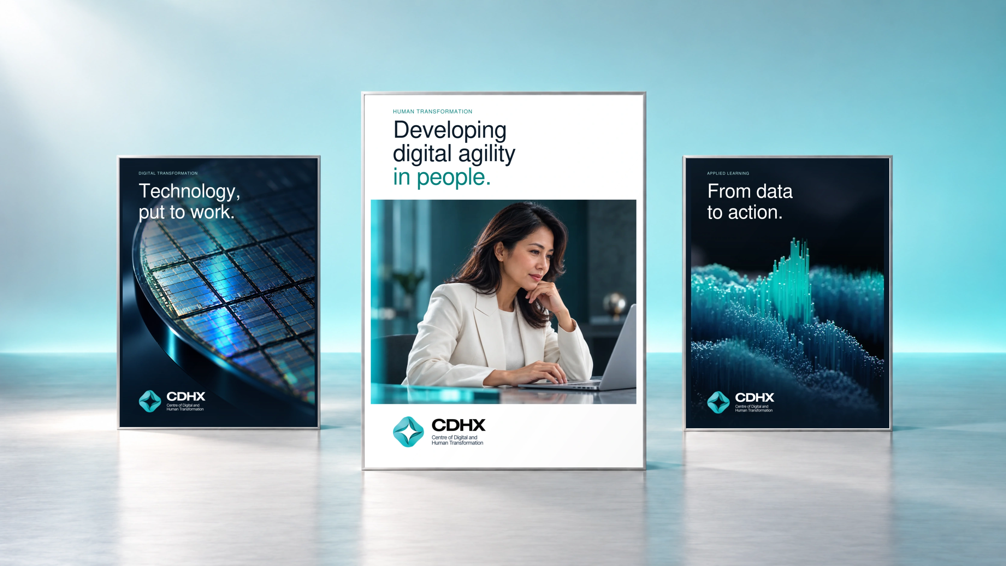 Three freestanding CDHX campaign boards in an aqua studio: a dark silicon wafer, a white central poster with a CDHX professional working at a laptop, and a dark data landscape. Exact CDHX logos and Nimbus typography.
