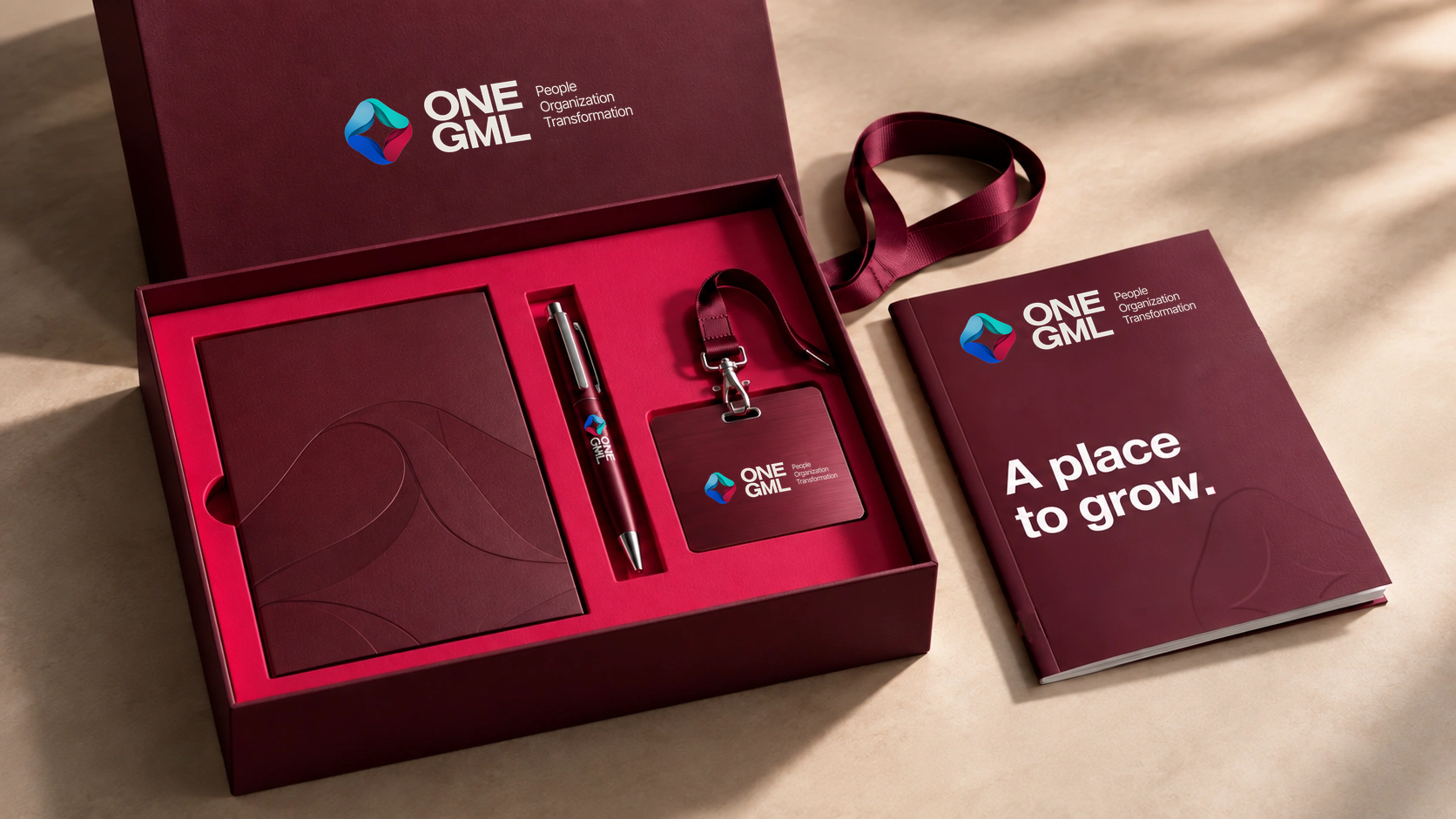 Burgundy ONE GML welcome kit with a colour logo on the pen and a large blind-embossed brand symbol on the standalone book cover.